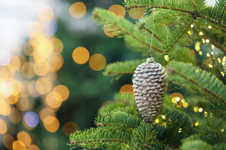 Beautiful Christmas tree with bauble in shape of cone against blurred lights, closeup and space for...