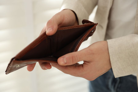 Poverty. Man with empty wallet indoors, closeup