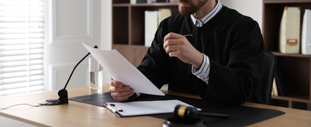 Serious judge in glasses working with documents at table in office