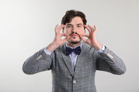 Handsome man with mustache on light backgroundの写真素材