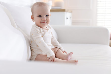 Cute little baby on sofa at home, space for text