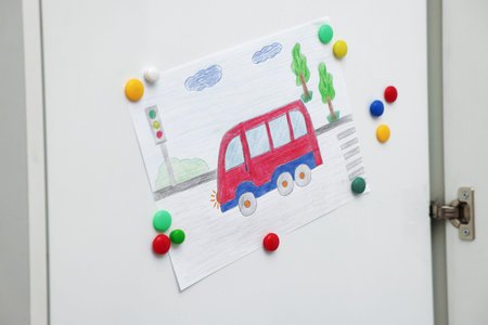 Child's drawing of bus on white cabinet indoors