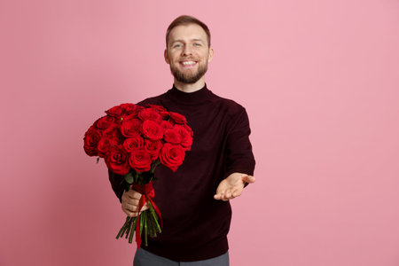 Man with bouquet of red roses on pink backgroundの写真素材
