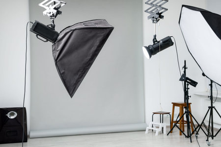 Professional lighting equipment hanging from ceiling in photo studio