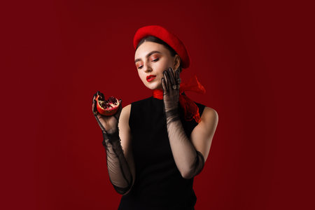 Beautiful woman with ripe pomegranate on red background