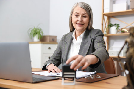 Notary taking stamp at wooden desk in office