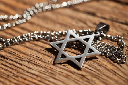 Holocaust Remembrance Day. Pendant in shape of Star of David and metal chain on wooden table,...