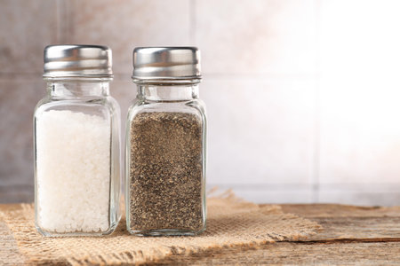 Salt and pepper shakers on wooden table, closeup. Space for text