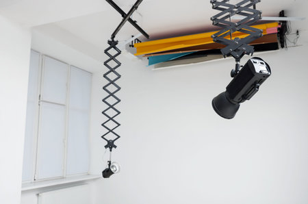 Professional lighting equipment hanging from ceiling in photo studio