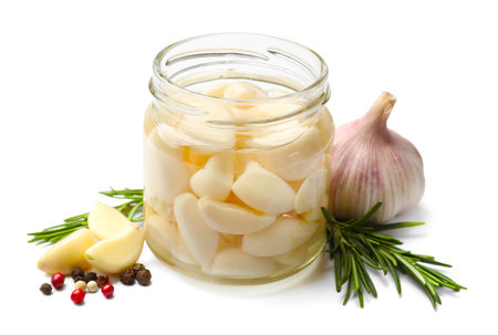 Pickled garlic in glass jar and spices isolated on whiteの写真素材