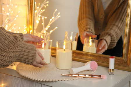 Woman arranging beautiful candles near mirror onto light wooden dressing table at home, closeupの写真素材