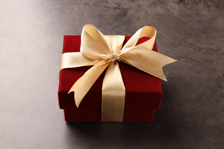 Red velvet gift box on grey table, closeup
