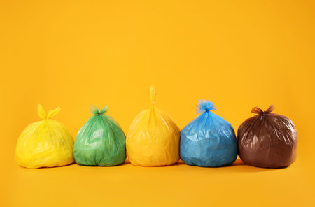 Garbage in colorful bags on yellow background. Space for textの写真素材