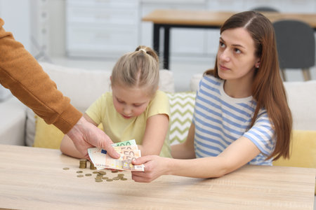 Alimony. Man giving money to his ex-wife and daughter at home, closeupの写真素材