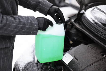 Woman with canister of antifreeze near car outdoors, closeup