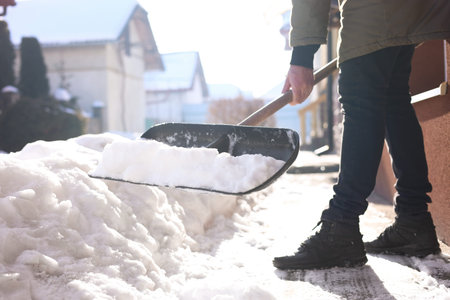 Man removing snow with shovel near building outdoors on winter day, closeupの写真素材
