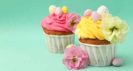 Tasty cupcakes with Easter decor on turquoise background, closeup. Space for text