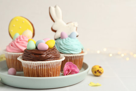 Tasty cupcakes with Easter decor on white table, closeup. Space for text