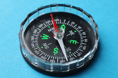 One compass on light blue background, closeup