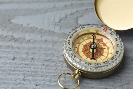One compass on gray wooden table, closeup. Space for text