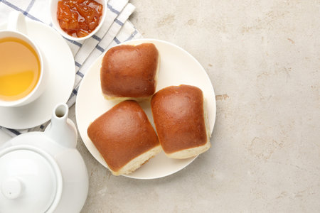Fresh buns, jam and tea on light table, flat lay. Space for text