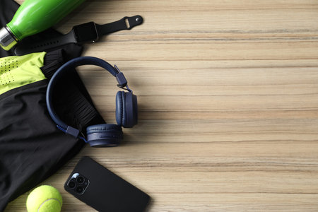 Headphones, smartphone, watch, water bottle, tennis ball and sports clothes on wooden background,...