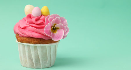 Tasty decorated Easter cupcake on turquoise background, closeup. Space for text