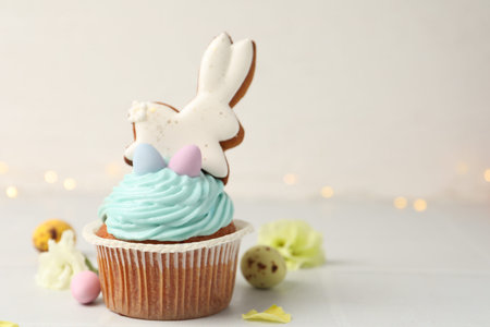 Tasty cupcake with Easter decor on white table, closeup. Space for text