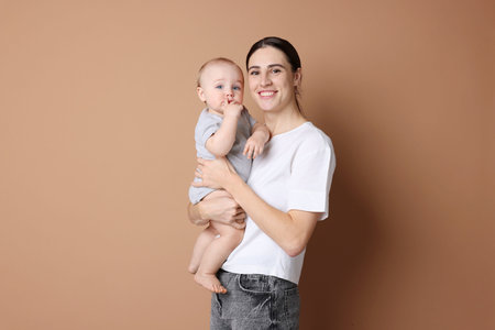 Happy mother with her cute baby on beige background
