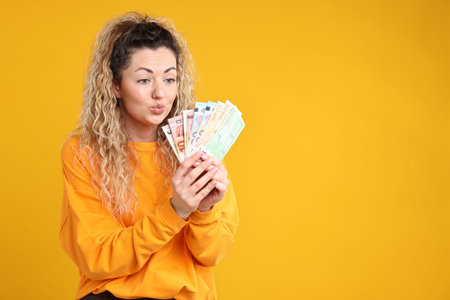 Sad woman with many euro banknotes on yellow background, space for text