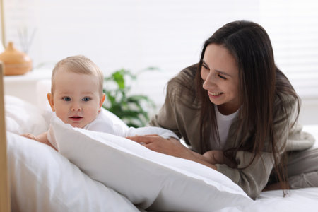 Mother with her cute baby boy on bed at home