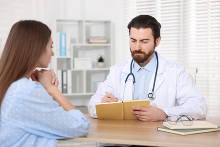 Woman having appointment with doctor at wooden desk in clinic
