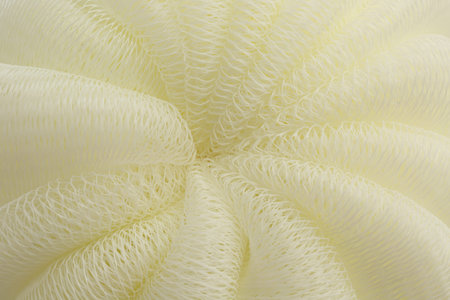 Beige mesh sponge as background, closeup. Shower accessory
