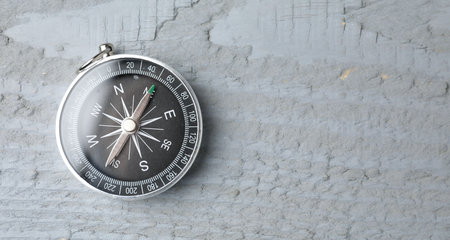 One compass on grey wooden table, top view. Space for text