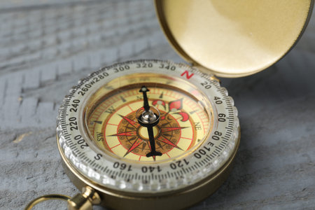 One vintage compass on grey wooden table, closeup