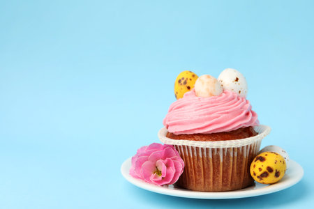 Tasty cupcake with Easter decor on light blue background, closeup. Space for text
