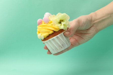 Woman with tasty decorated Easter cupcake on turquoise background, closeup