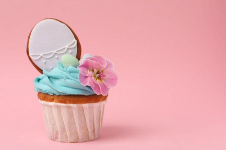 Tasty decorated Easter cupcake on pink background, closeup. Space for text