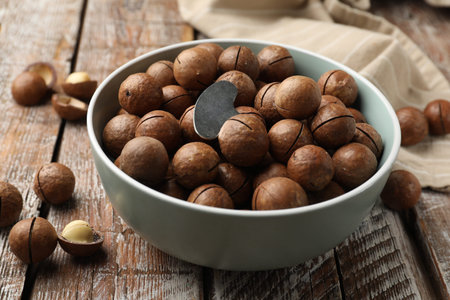 Macadamia nuts and metal key in bowl on wooden table, closeupの写真素材
