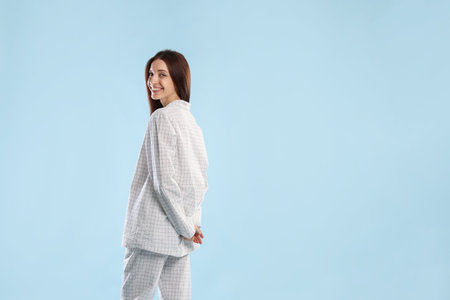 Beautiful woman in stylish pajamas on light blue background. Space for text