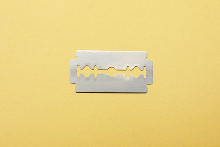 One sharp blade on yellow background, top view