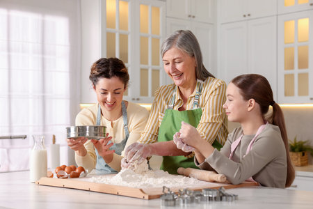Grandmother, her daughter and granddaughter cooking together at white marble table in kitchen