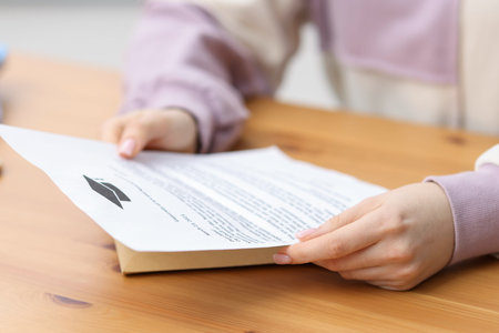 Woman with letter from university at wooden table indoors, closeup
