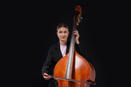 Girl playing double bass on black background