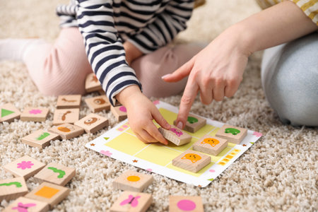Mother and her daughter playing with toys on floor at home, closeup