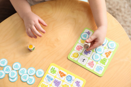 Cute little boy playing with toys at wooden table indoors, above view
