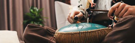 Woman playing steel tongue drum with mallets at home, closeupの写真素材