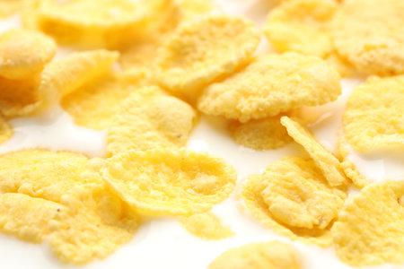 Tasty corn flakes with milk as background, closeup