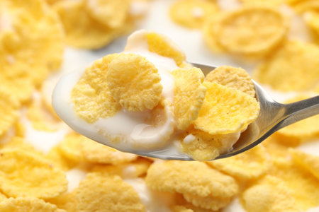 Spoon with tasty corn flakes and milk, closeup
