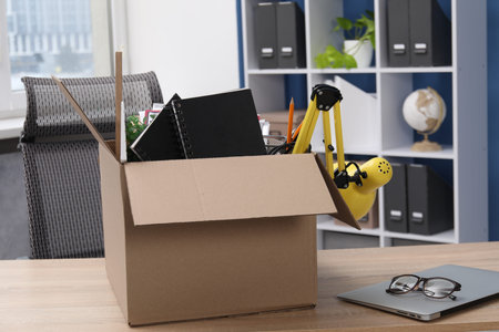 Dismissal. Box of personal belongings on desk in office